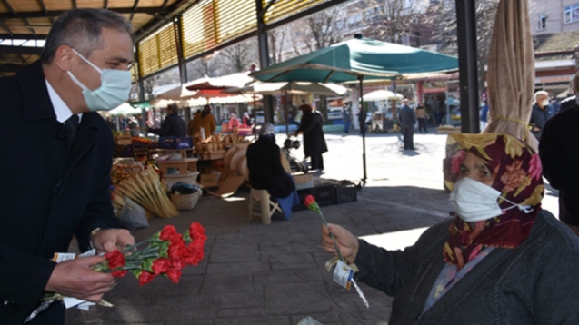Pazaryerinde karanfil ve maske dağıtarak kutladı.